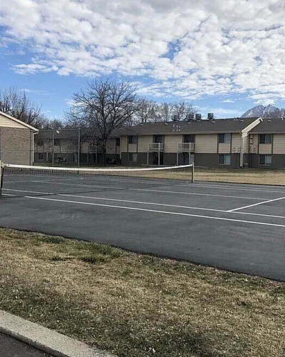 Community tennis court with apartment buildings beyond at Braewood in Murray, UT