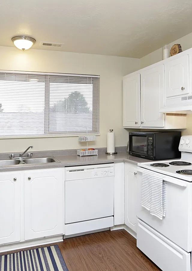 Bright kitchen with white cabinets and a window over the sink at Braewood in Murray, UT