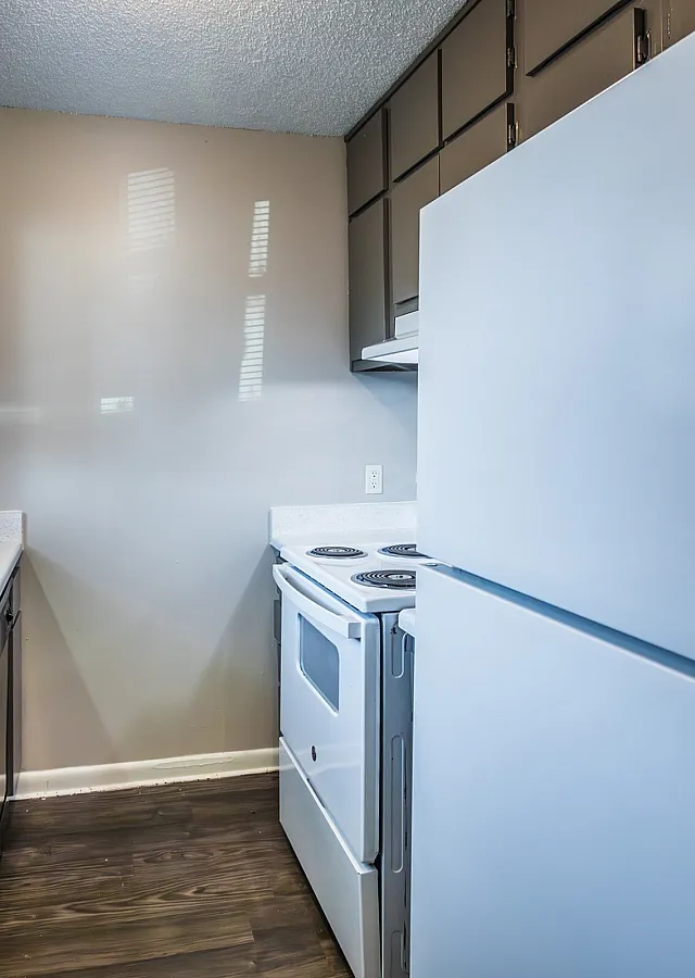 Kitchen with dark cabinets and white appliances at Collier Village Apartments in Collierville, TN
