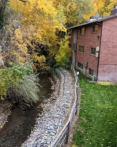 Creek and autumn trees next to a brick building at Fairbrook in Salt Lake City, UT