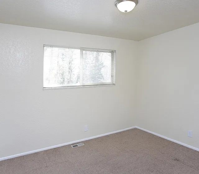 Bright carpeted bedroom with a window at Fairbrook in Salt Lake City, UT