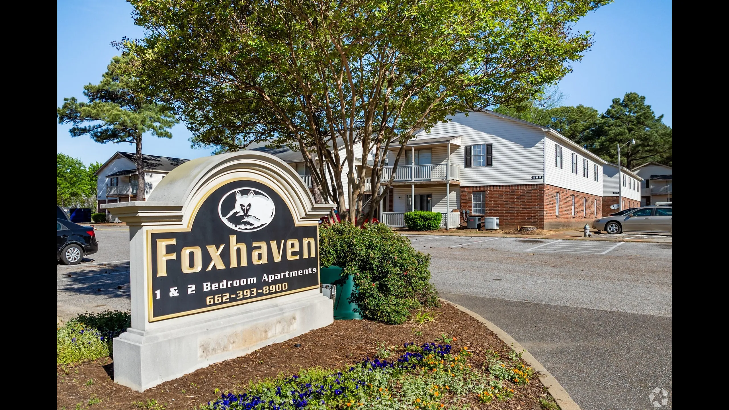 Entrance sign framed by landscaping and shade trees at Foxhaven Apartments in Southaven, MS