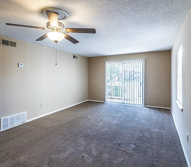 Living room with ceiling fan and large window at Foxhaven Apartments in Southaven, MS