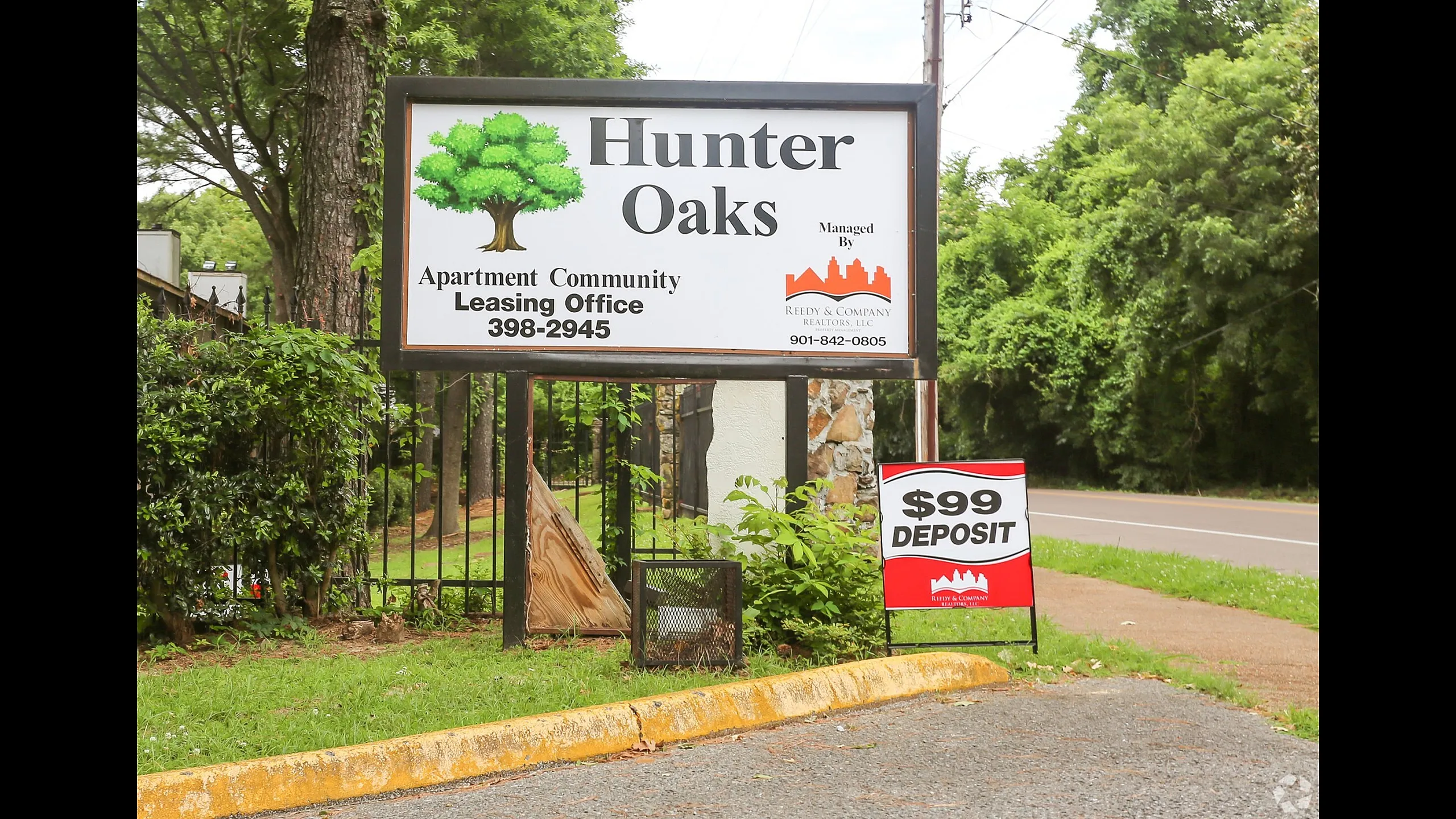 Community leasing sign framed by green trees at Hunter Oaks Apartments in Memphis, TN