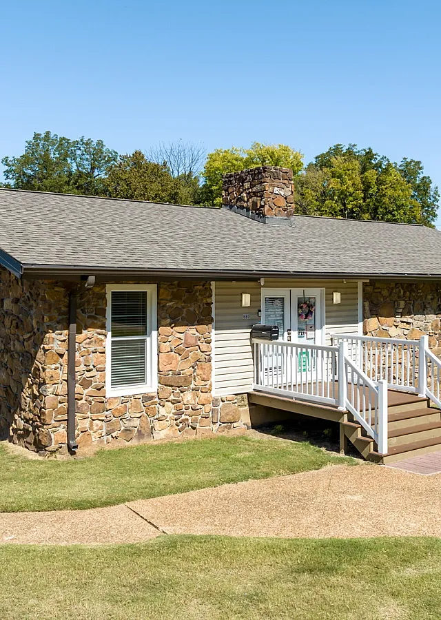 Stone clubhouse and leasing office with a front porch at Hunter Oaks Apartments in Memphis, TN