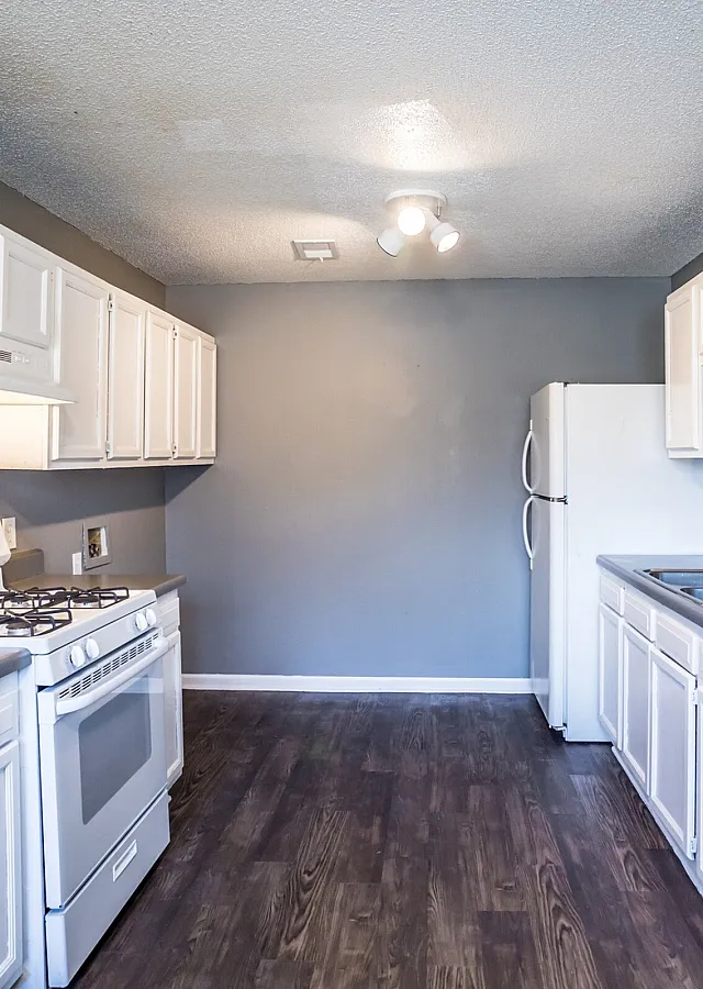 White galley kitchen with wood-style floors at Jackson Heights Residential in West Memphis, AR
