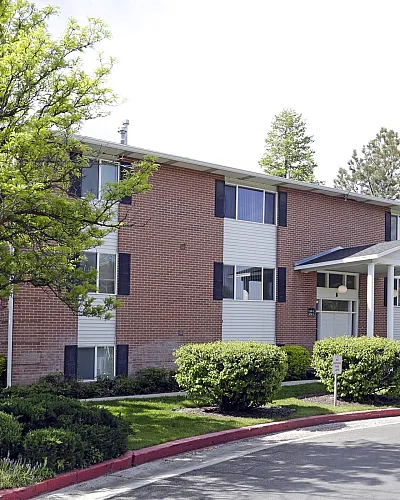 Brick apartments surrounded by mature shade trees at Linden Colonial in Holladay, UT
