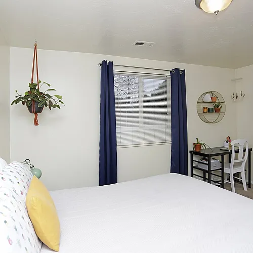 Bedroom with a queen bed and blue curtains at Linden Colonial in Holladay, UT