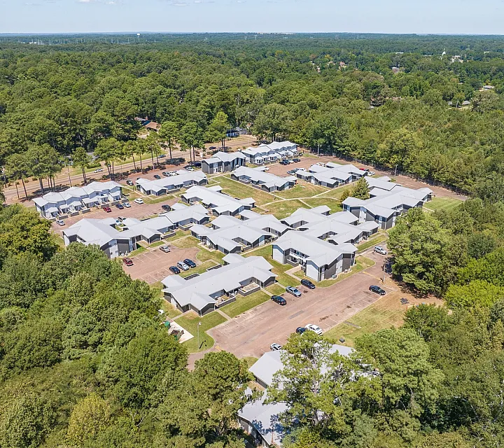 Aerial overview of the community among pine woods at Pines Apartments in Jackson, MS