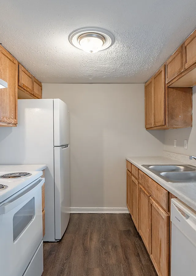 Townhome kitchen with wood cabinets and white appliances at Pines Apartments in Jackson, MS