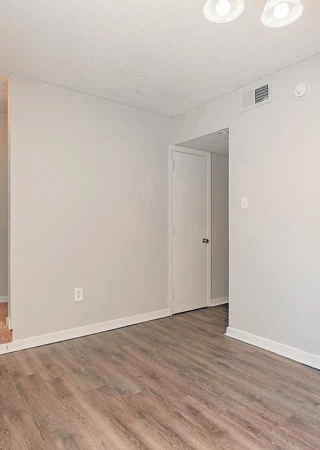Open living and dining area with wood-style floors at Pines Apartments in Jackson, MS