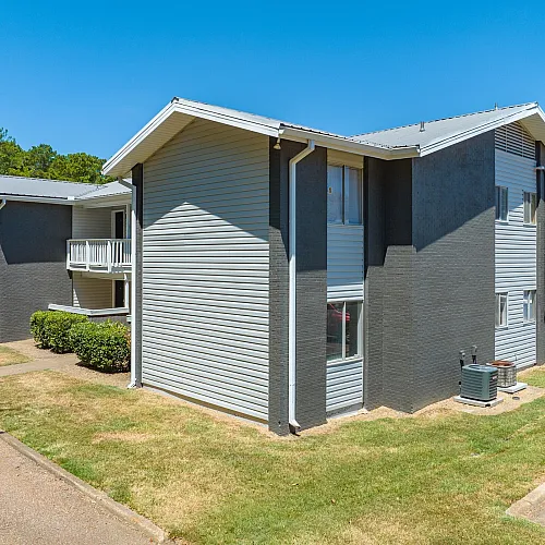 Gray and white buildings along a sidewalk at Pines Apartments in Jackson, MS