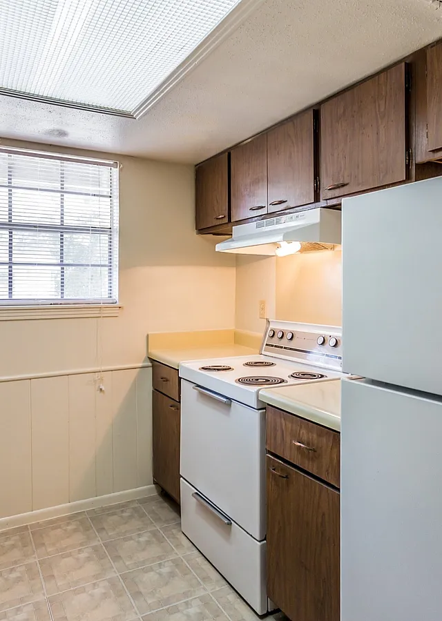 Kitchen with wood cabinets and white appliances at Windsor Place Apartments in Memphis, TN