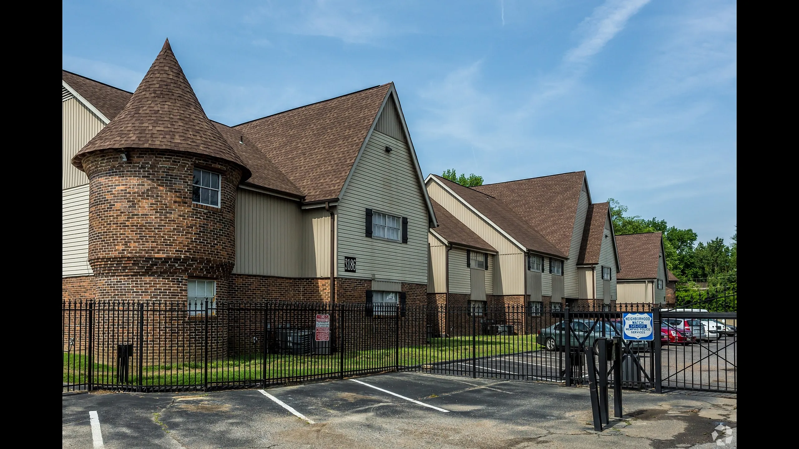 Brick turret building beside gated parking at Windsor Place Apartments in Memphis, TN