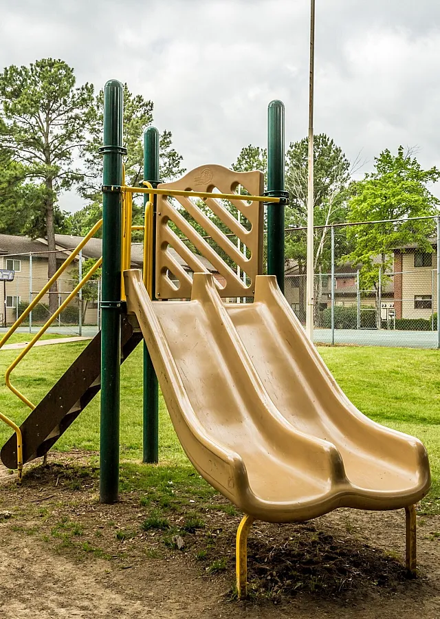 Playground with a yellow slide on a grassy lawn at Hickory Pointe in Memphis, TN