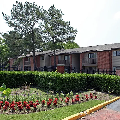 Red flower bed and hedges in front of brick buildings at Hickory Pointe in Memphis, TN