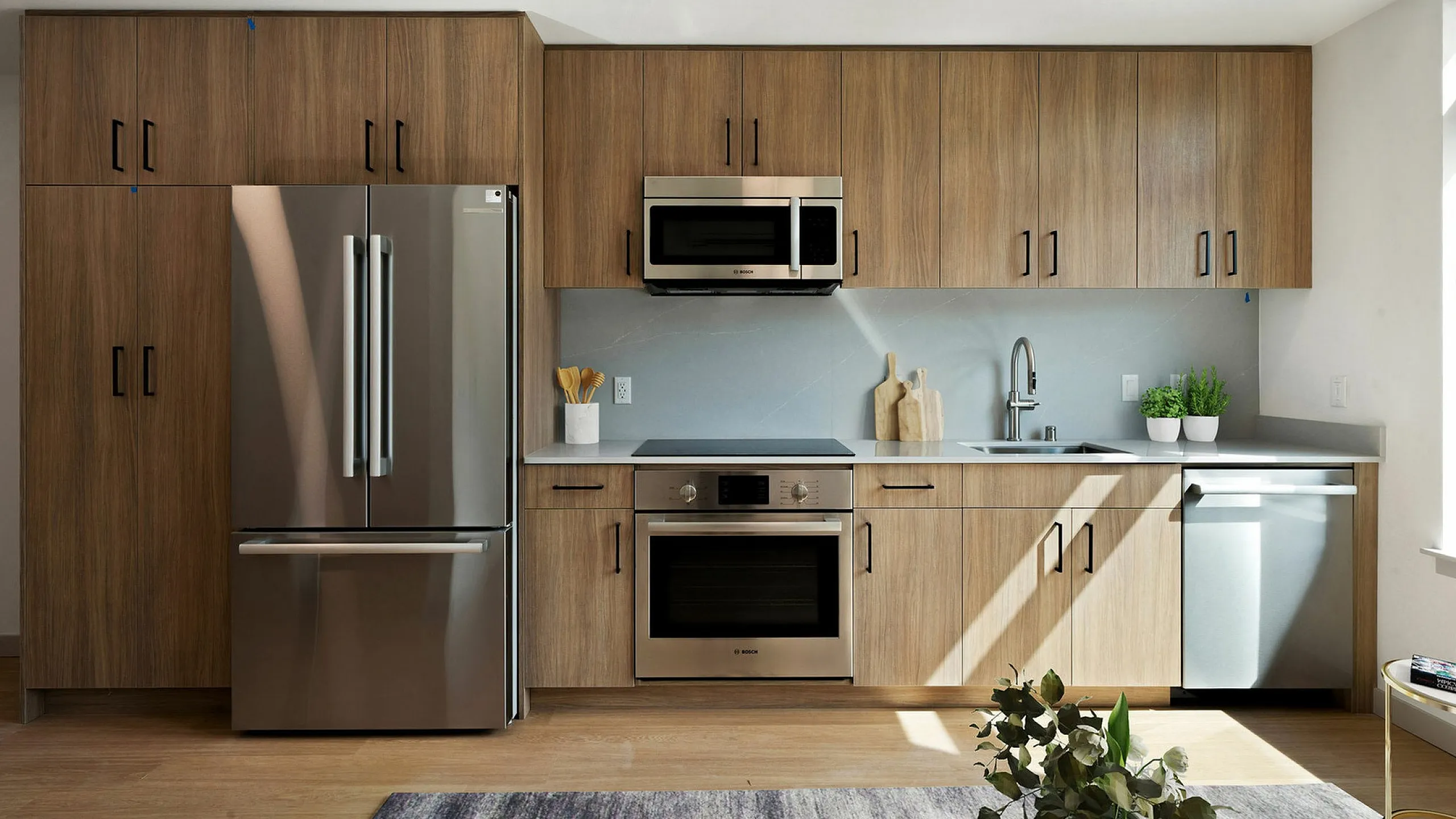 Elegant modern kitchen with sleek stainless steel appliances, stylish wooden cabinets, and abundant natural light.