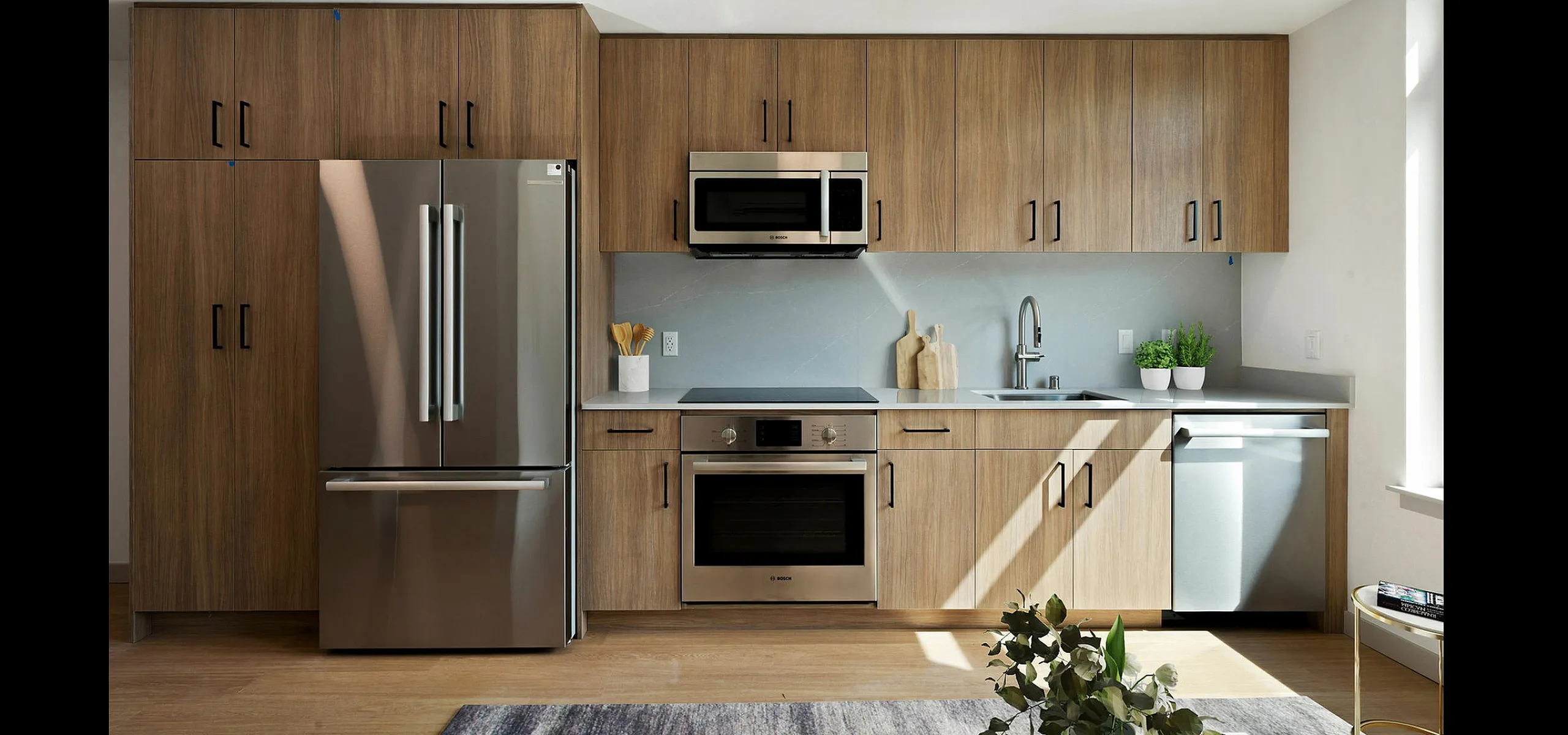 Modern kitchen featuring sleek wooden cabinets, stainless steel appliances, and bright natural lighting.