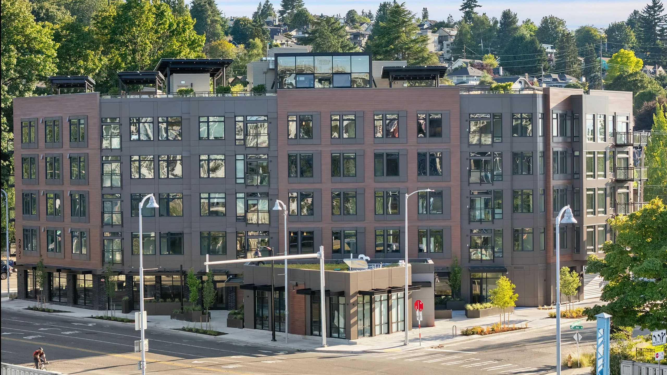 Contemporary urban apartment building surrounded by lush greenery, featuring a stylish design and ample natural light.