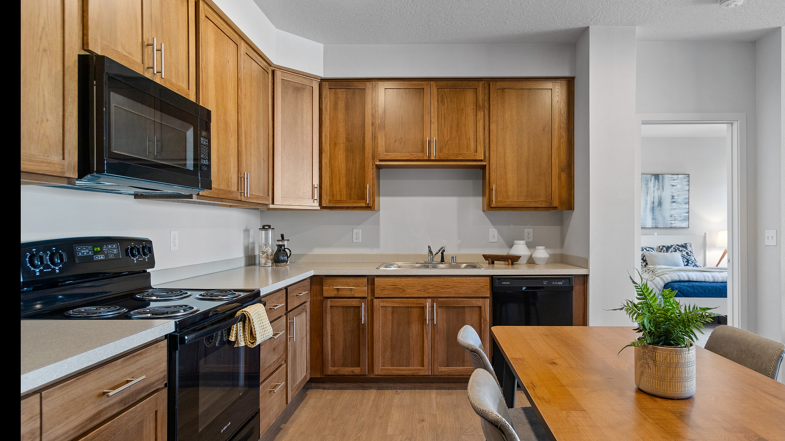 Warm and inviting kitchen with wooden cabinetry, modern appliances, and a sleek dining table.