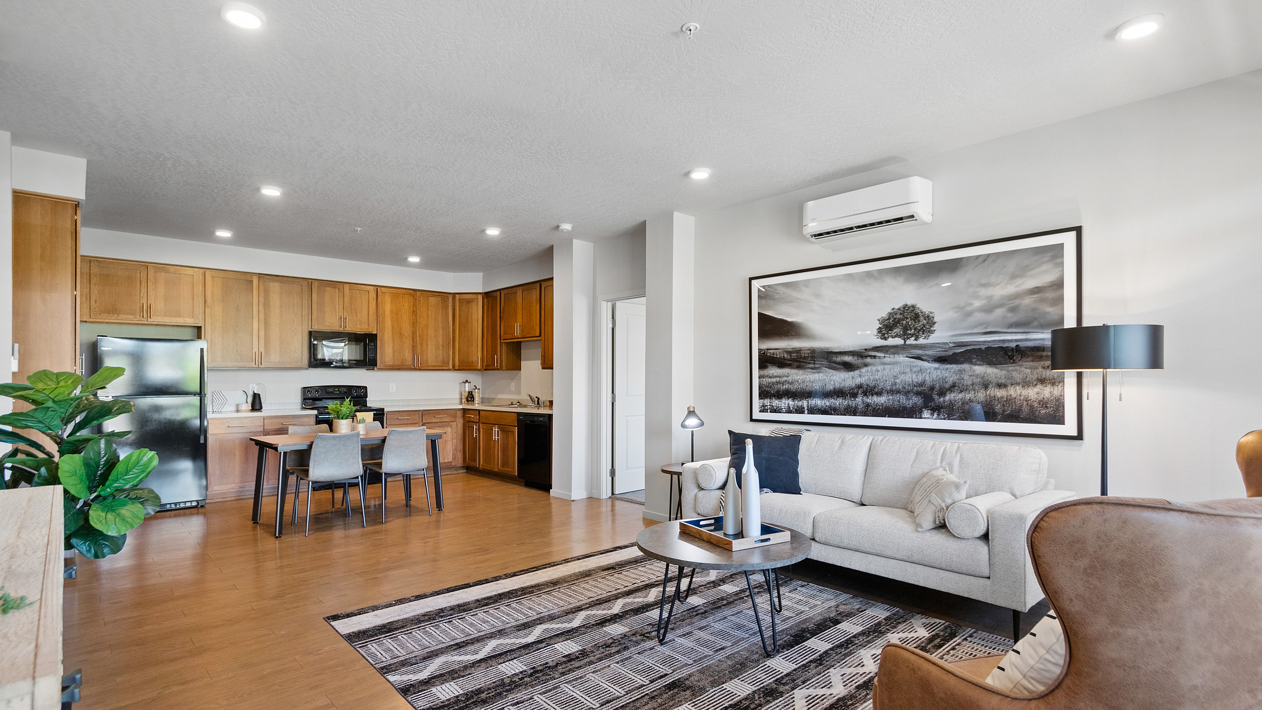 Modern open-concept living room with a cozy sofa, stylish armchair, elegant kitchen, and vibrant decor.