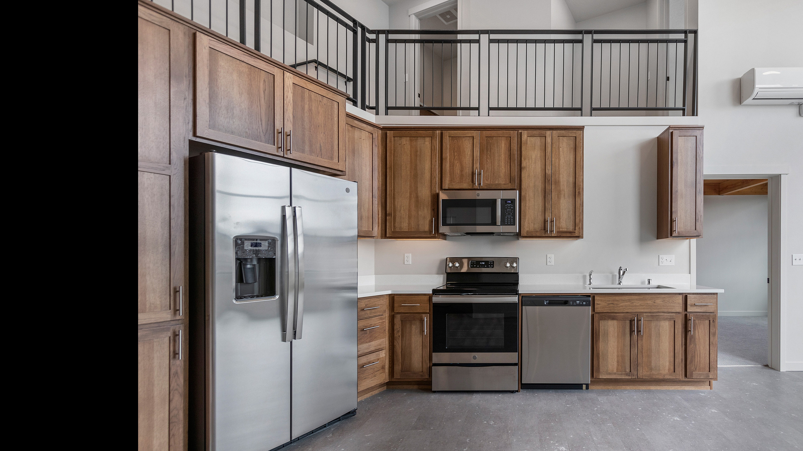 Modern kitchen with sleek stainless steel appliances and elegant wooden cabinetry, featuring a spacious loft design.