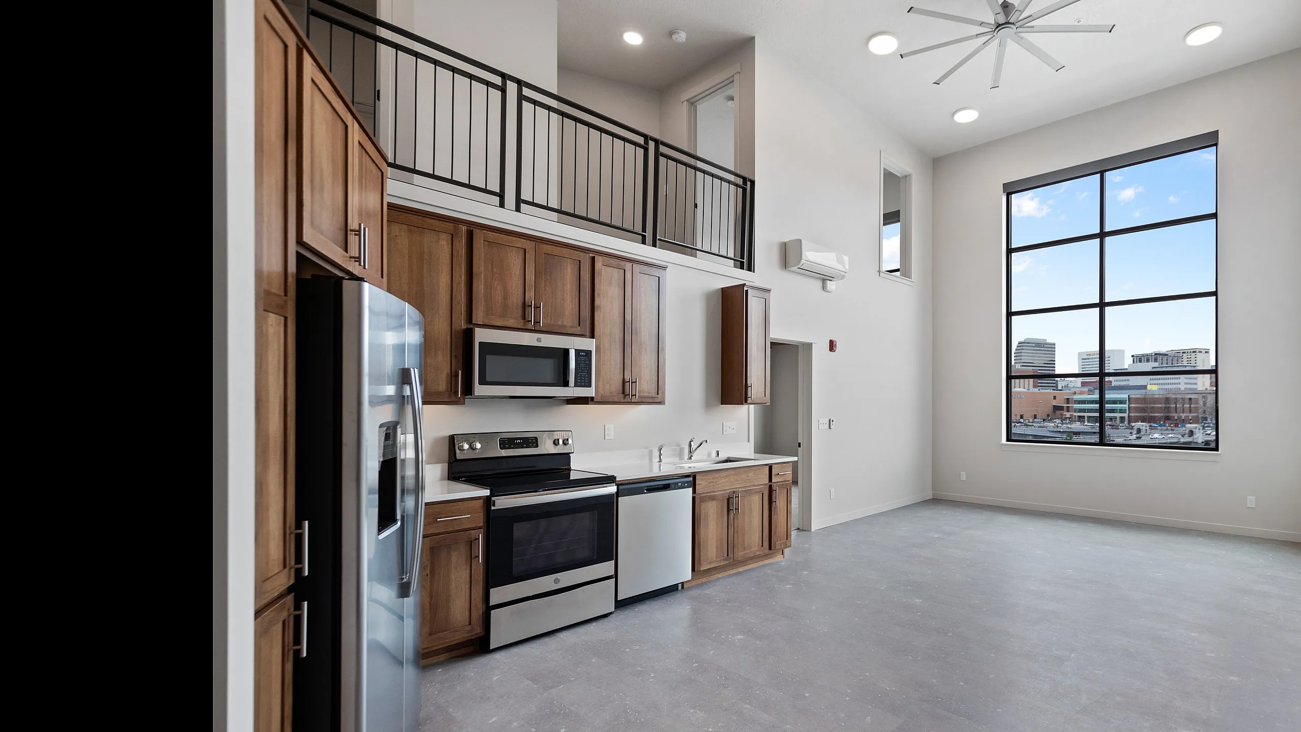 Modern loft apartment with high ceilings, expansive city view window, and sleek kitchen featuring stainless steel appliances.