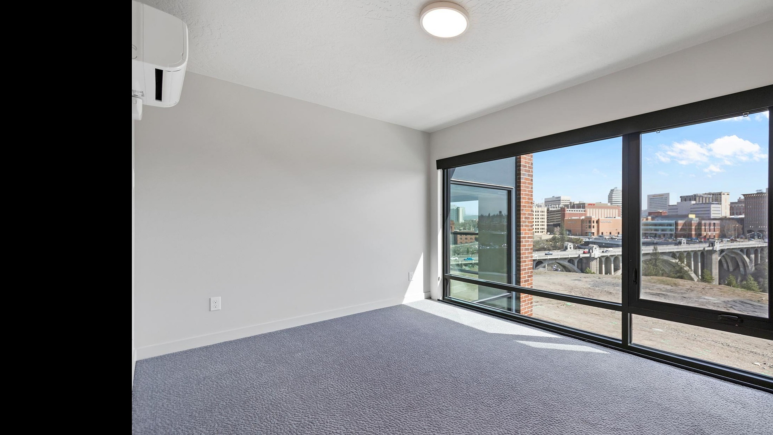 Bright and airy room featuring expansive windows with a stunning cityscape view, perfect for a modern apartment living experience.