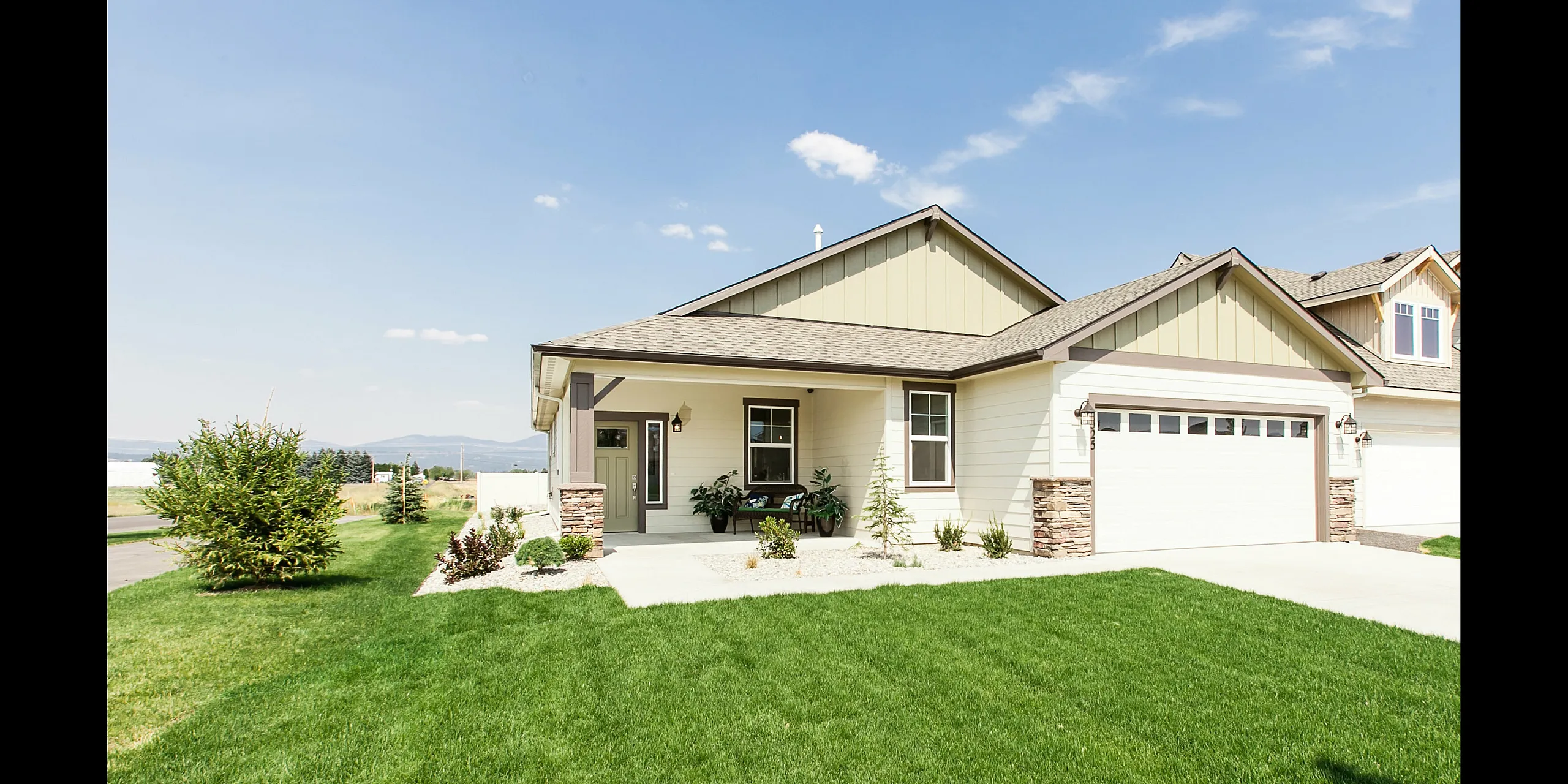 Charming suburban home with modern exterior, landscaped front yard, and spacious driveway under a clear blue sky.