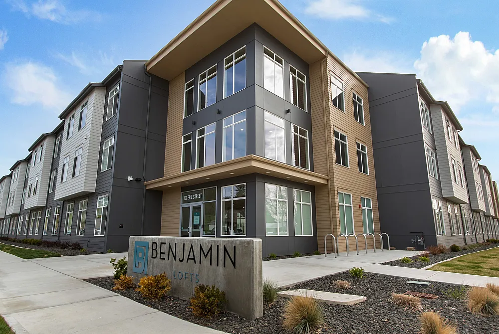 Modern Benjamin Lofts exterior showcasing sleek architecture with large windows and well-maintained landscaping under a bright blue sky.