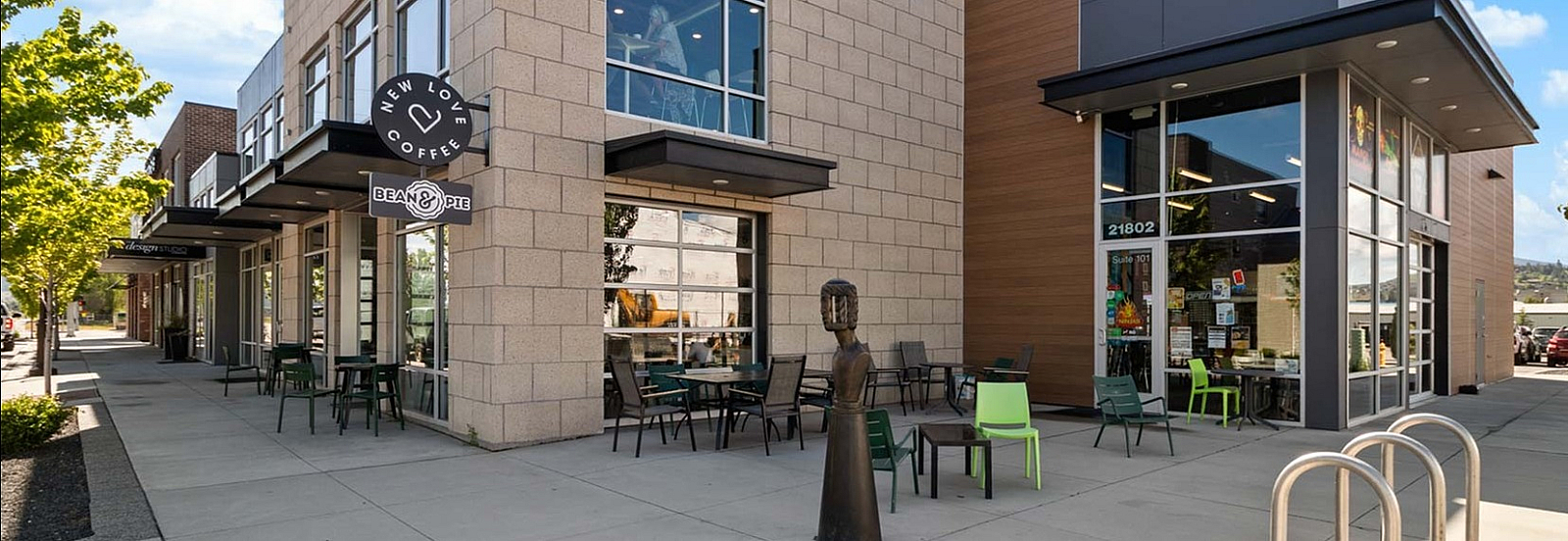 Chic urban retail space featuring modern architecture with large glass windows, outdoor seating, and contemporary design elements.