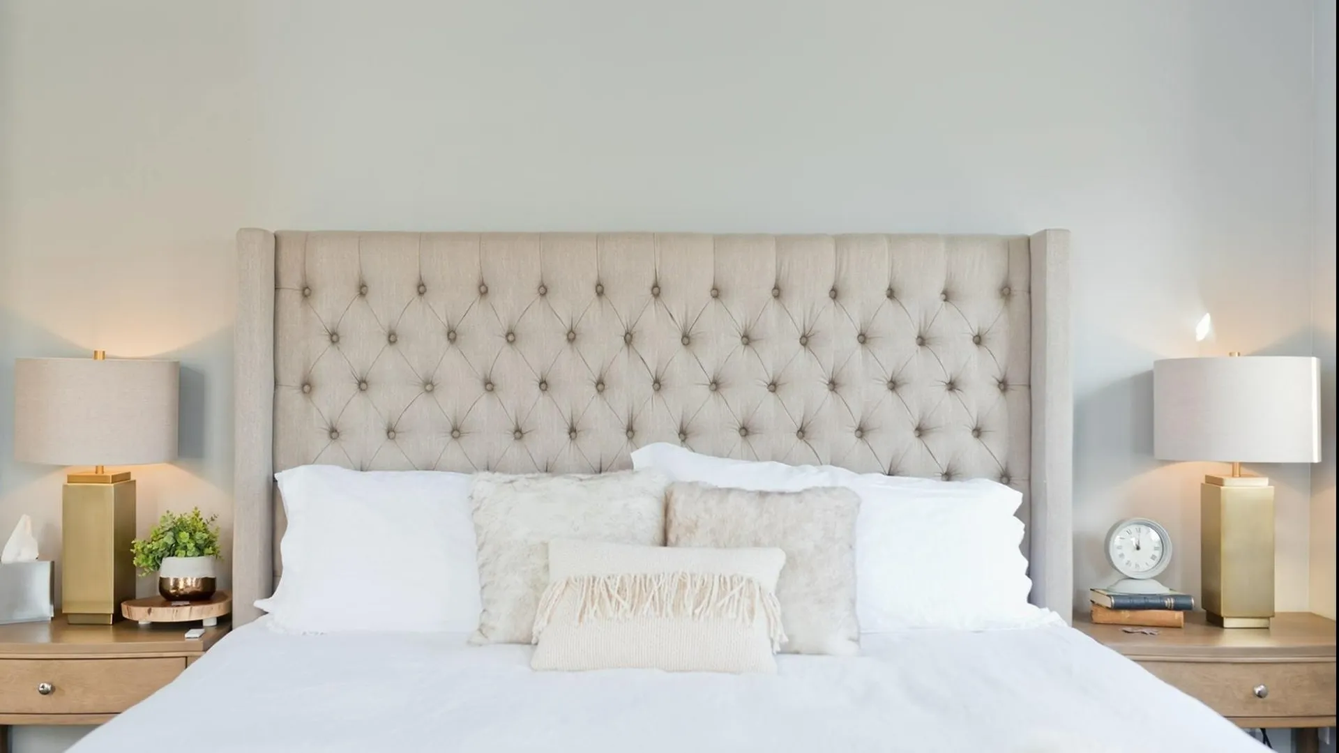 Queen bed with quilted headboard and pillows, side tables and lamps.