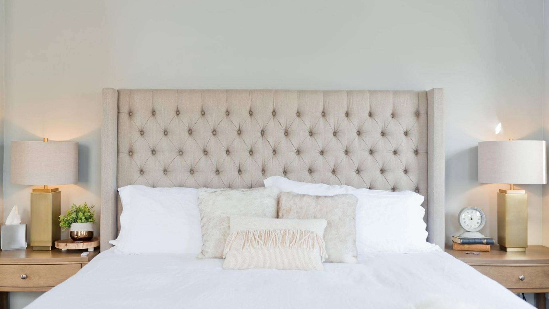 Queen Bed with quilted headboard and white bedspread, side tables with lamps and books.