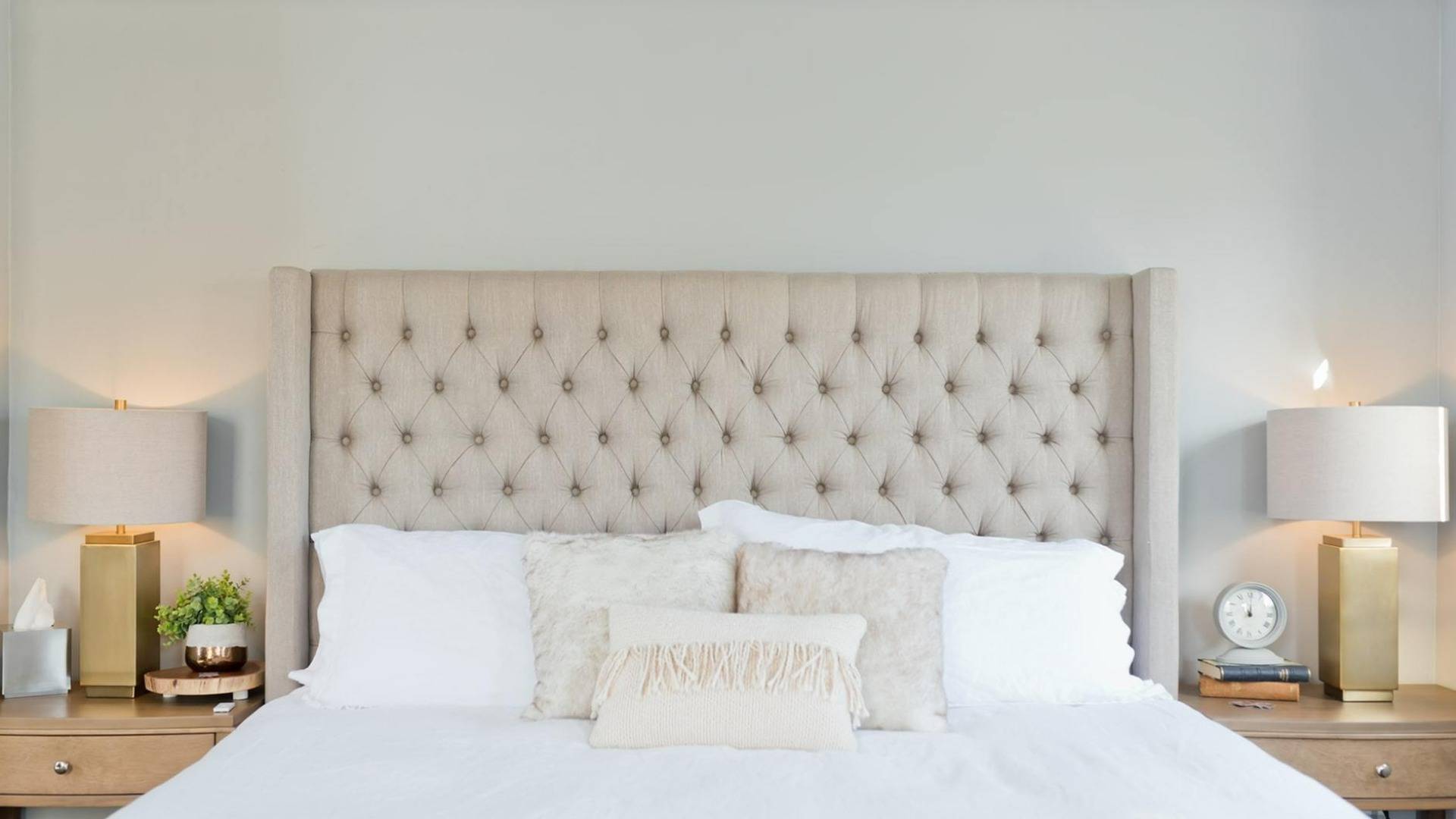 Queen Bed with quilted headboard and white bedspread, side tables with lamps and books.