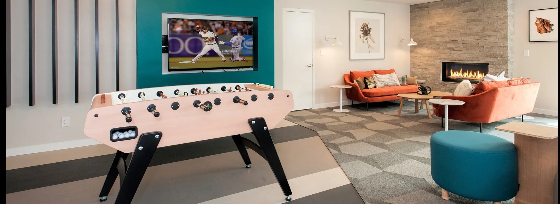 Clubhouse with TV, foosball table, couches and a fireplace.