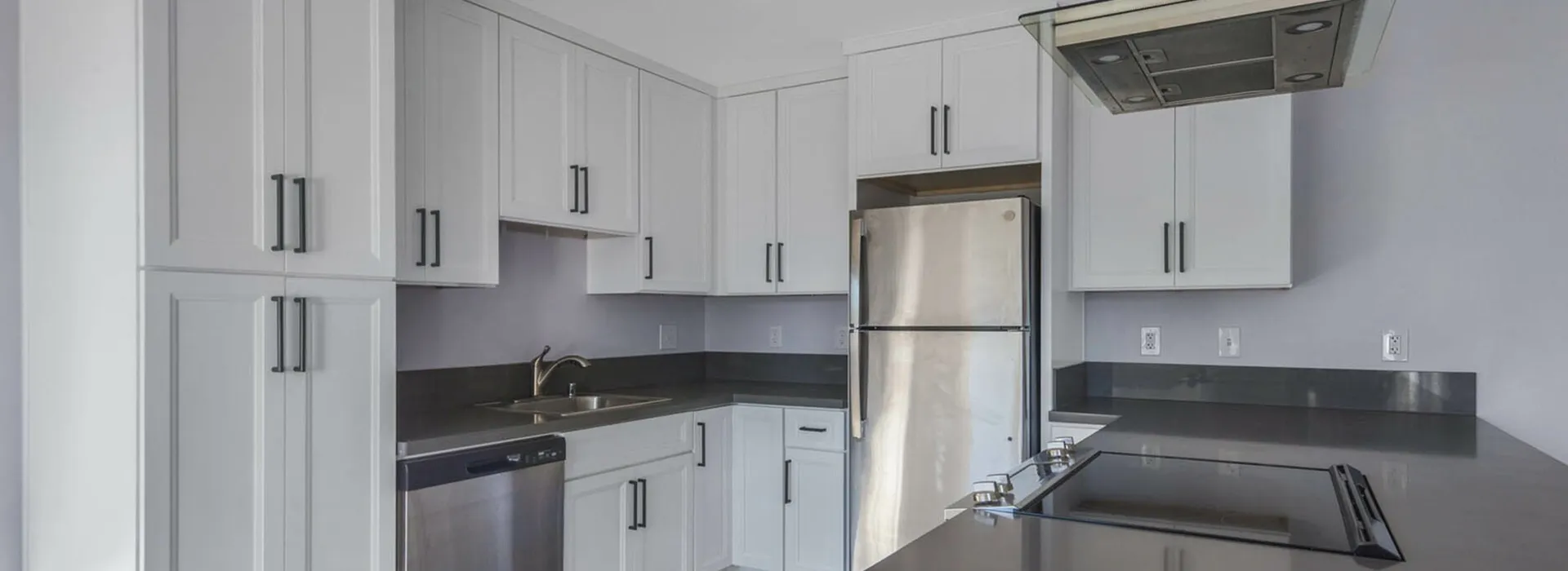 Kitchen with stainless steel appliances and modern white cabinetry.