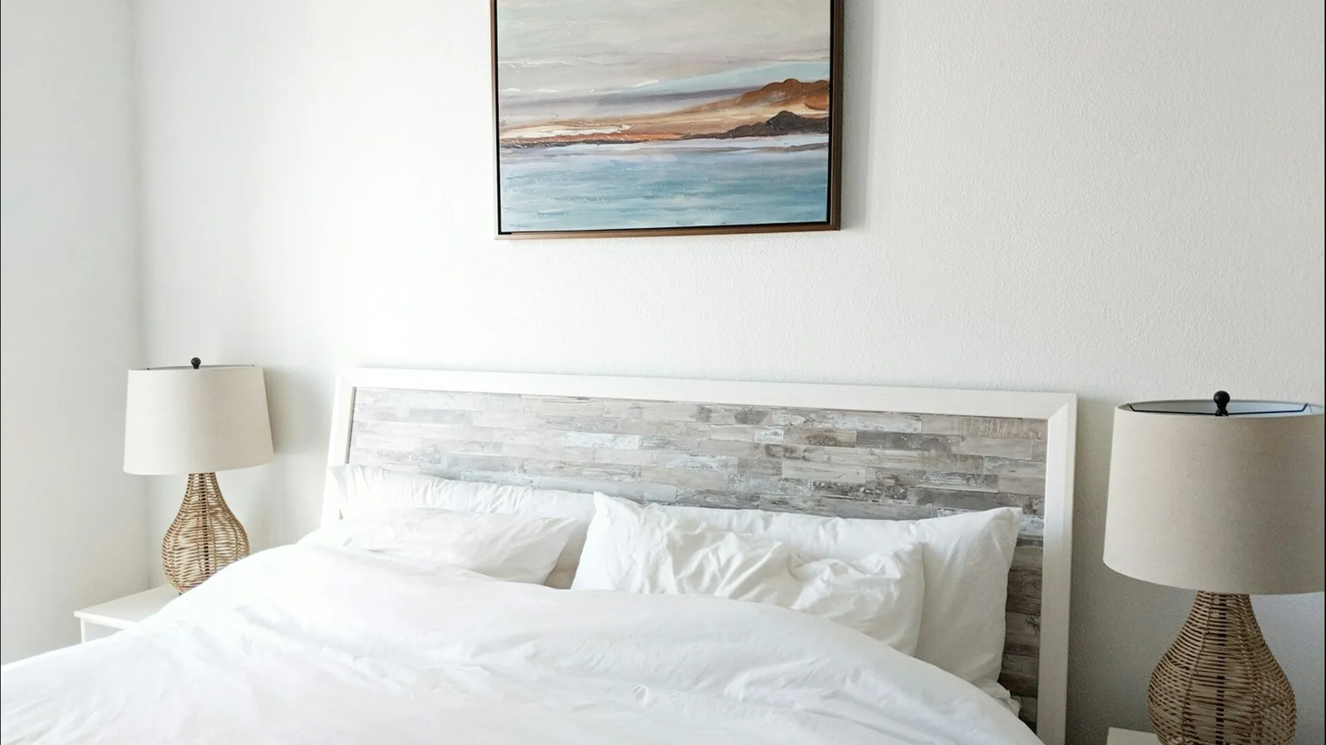 Bed with blue ocean painting hanging above
