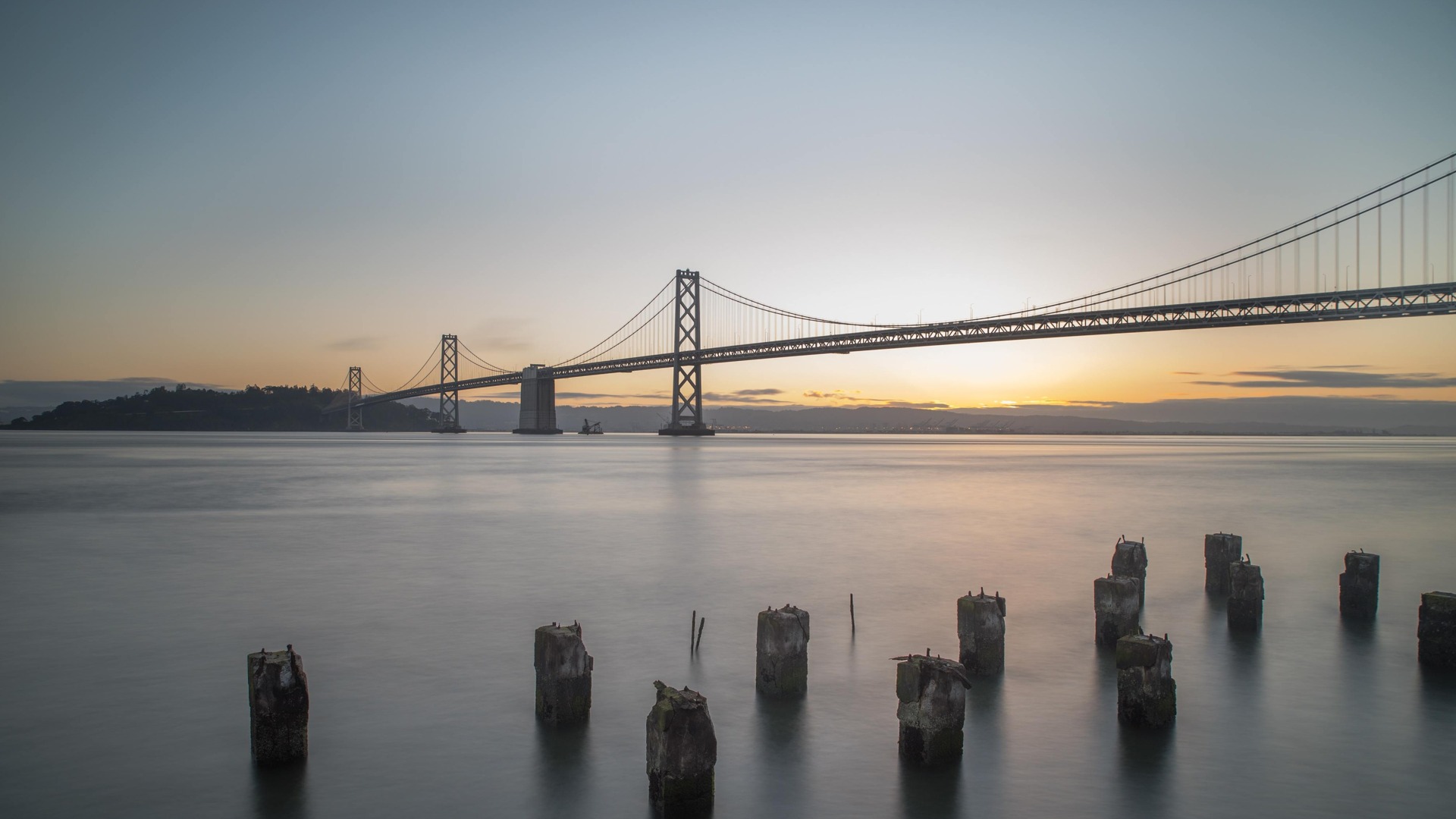 bay bridge above the san fransicso bay leading to treasure island. The sunrise is in the background