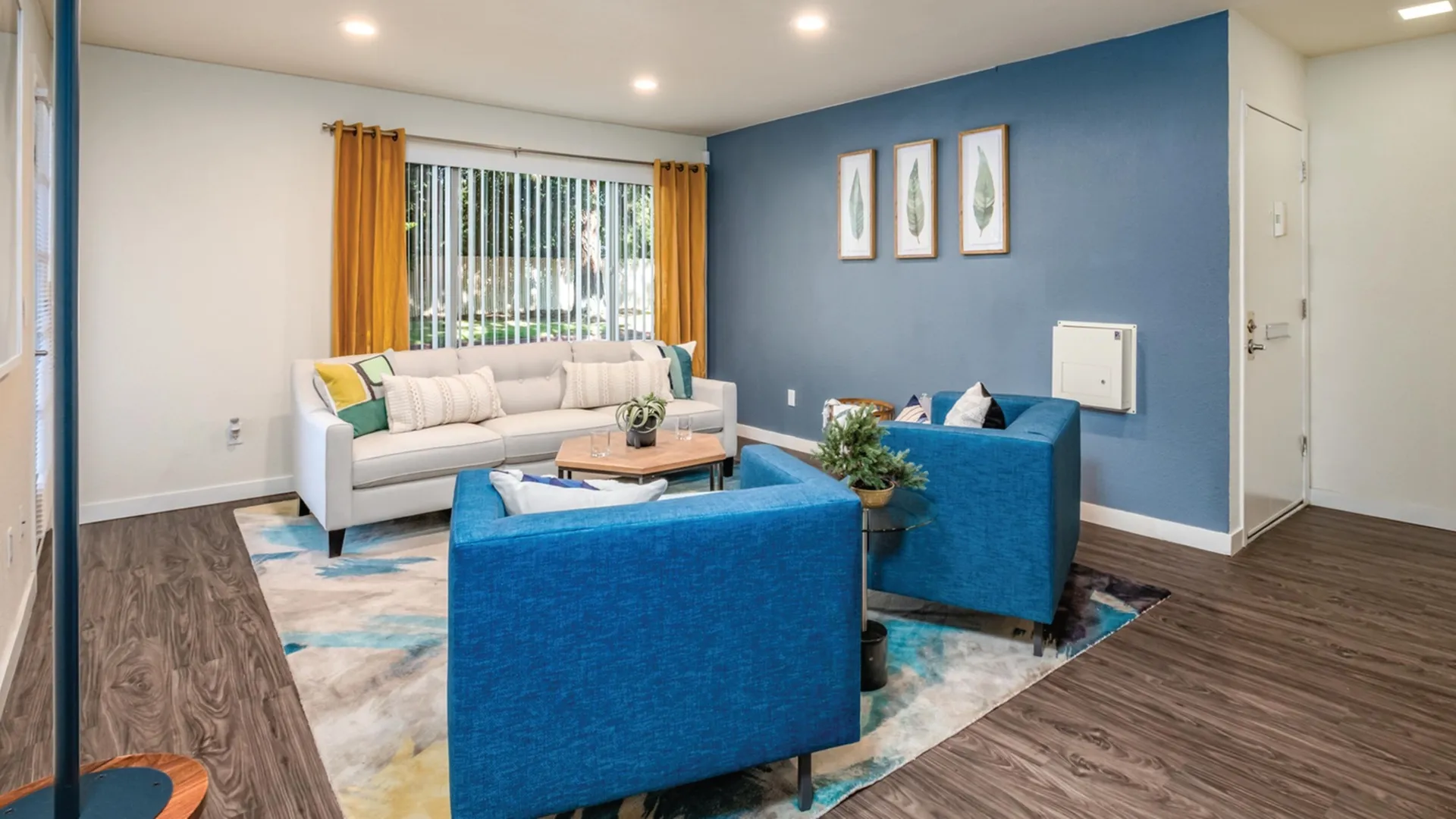 White couch under window faced by two blue chairs.