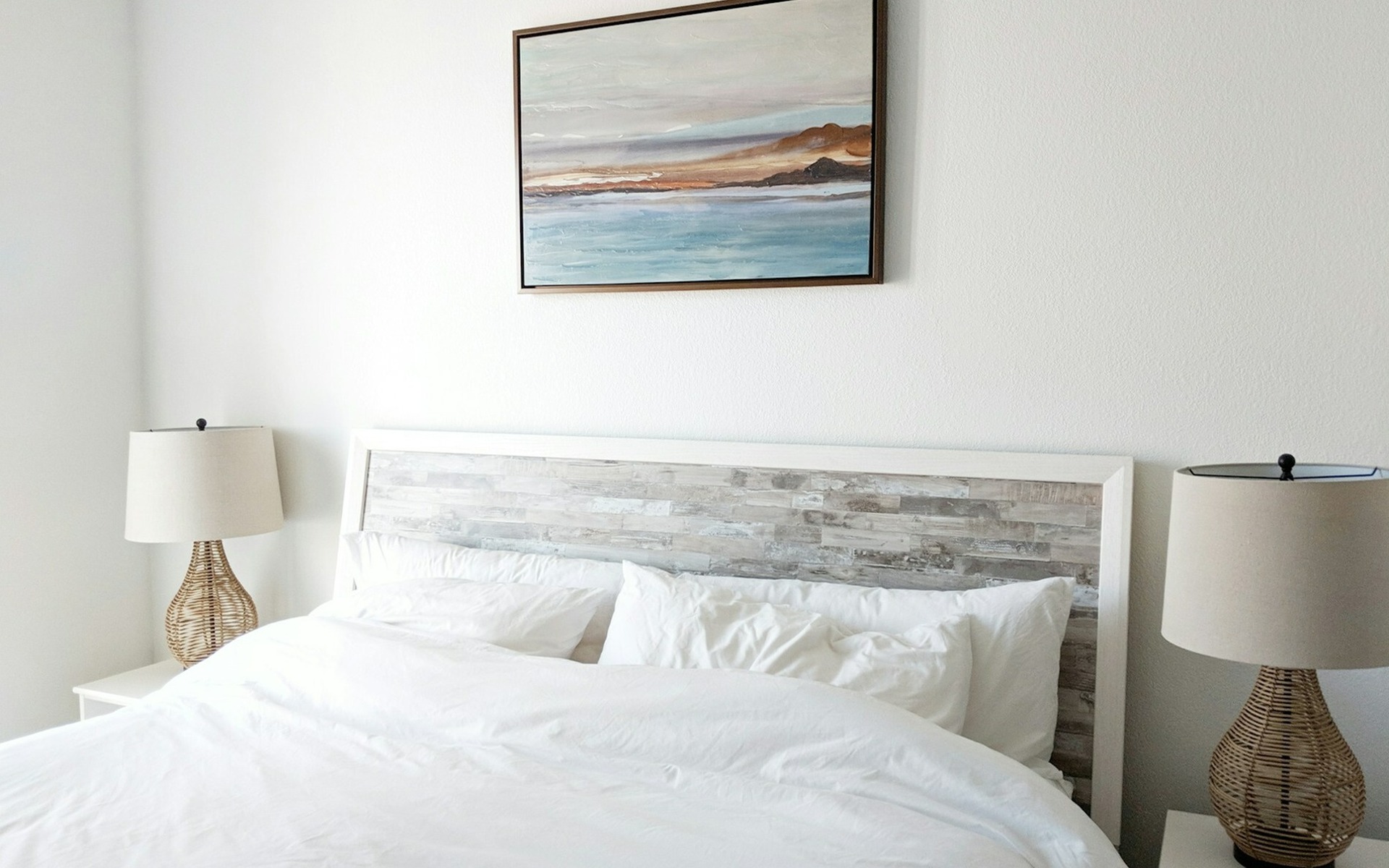 Bed with blue ocean painting hanging above