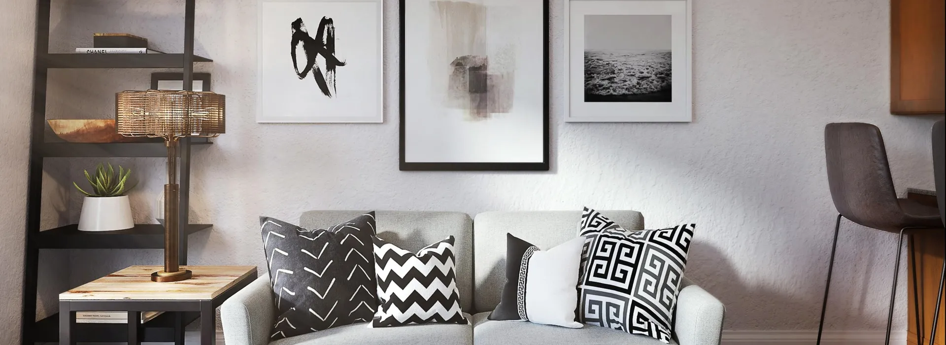 grey couch with fluffy pillows. side table and selves on left side of couch. black and white art on back wall.
