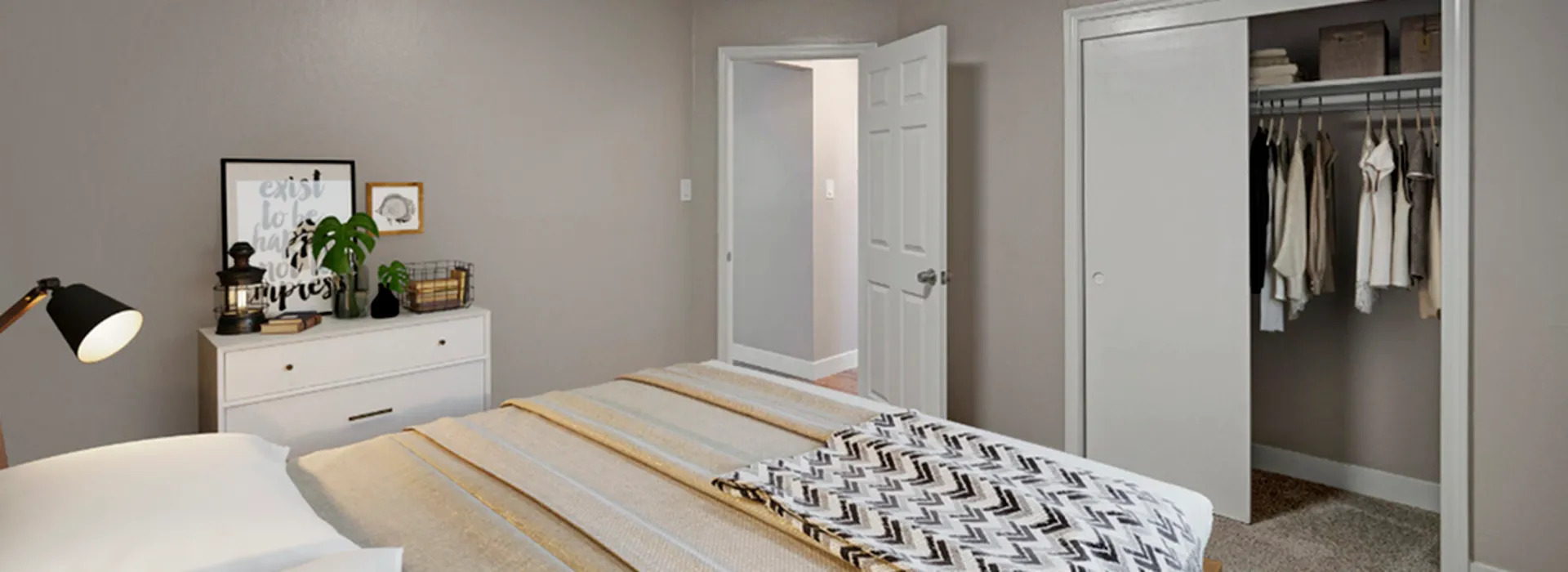 cozy bedroom with closet full of hanging clothes, and drawer to left side of bed with decorations