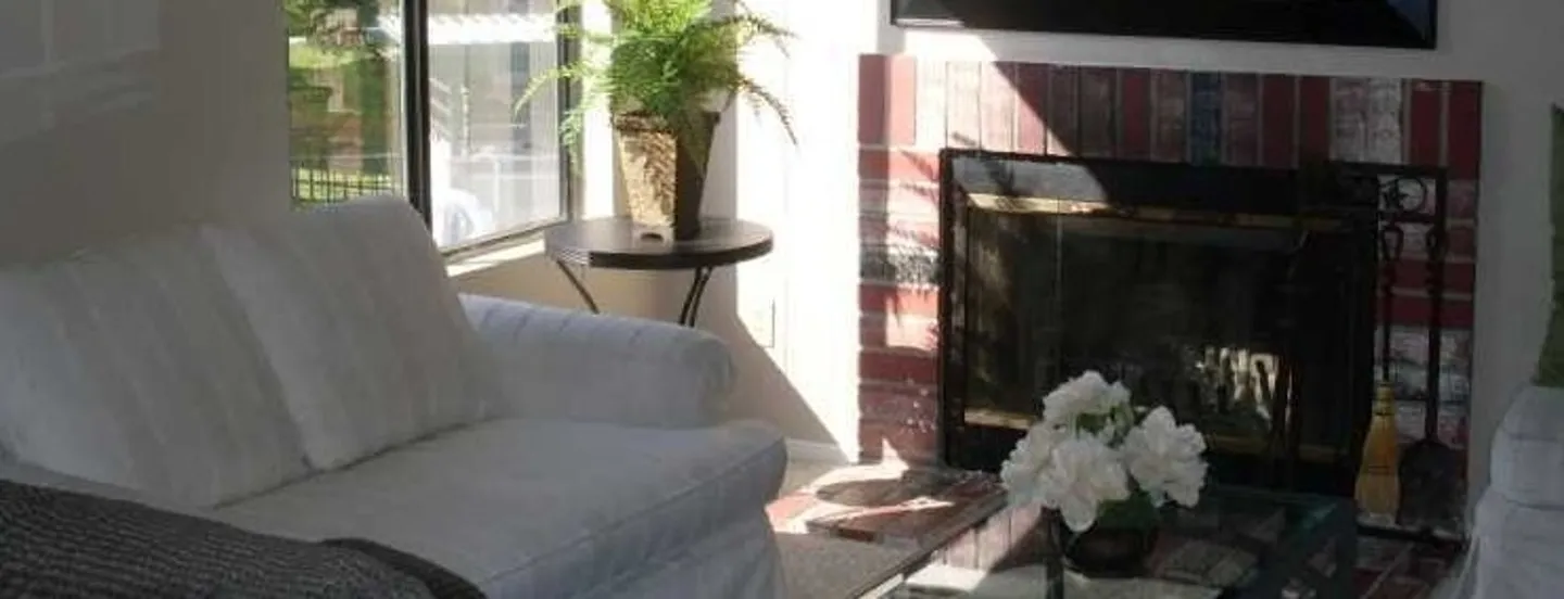 comfy white couch next to fireplace and open window