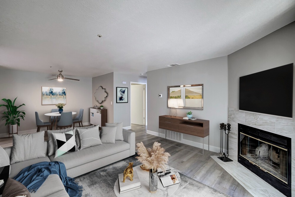 Exterior photo of the community showing two-story apartment building with stairs leading up to second story. Apartments have walled balconies / patios. Wood trellis with blossoming flowers and surrounded by full shrubs and landscaping in th