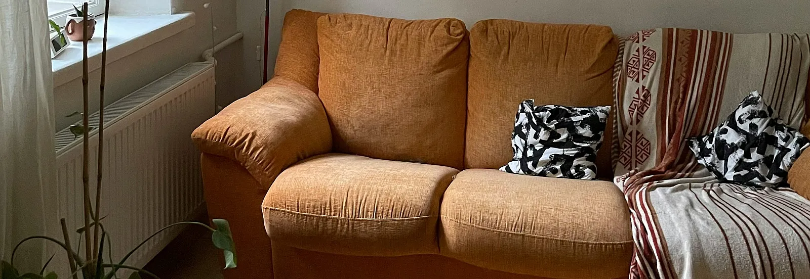 An orange couch with black and white throw pillows