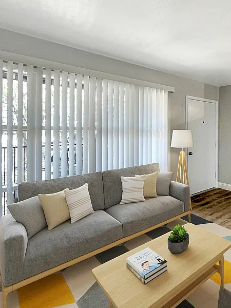 Living room with grey couch, beige and white throw pillows and a colorful rug