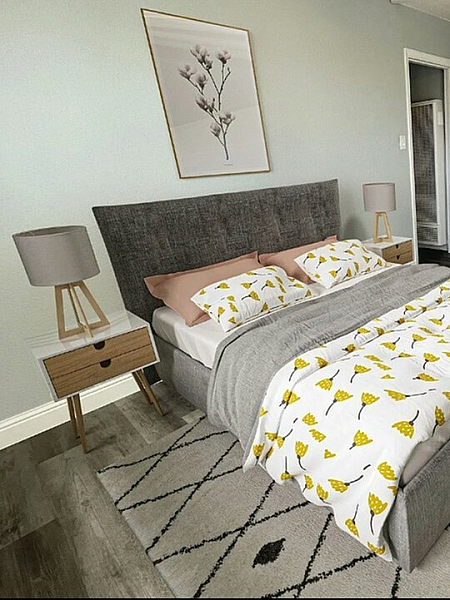 Modern bedroom with a gray upholstered bed, yellow floral bedding, and matching nightstands. A framed botanical print hangs above, creating a cozy ambiance.