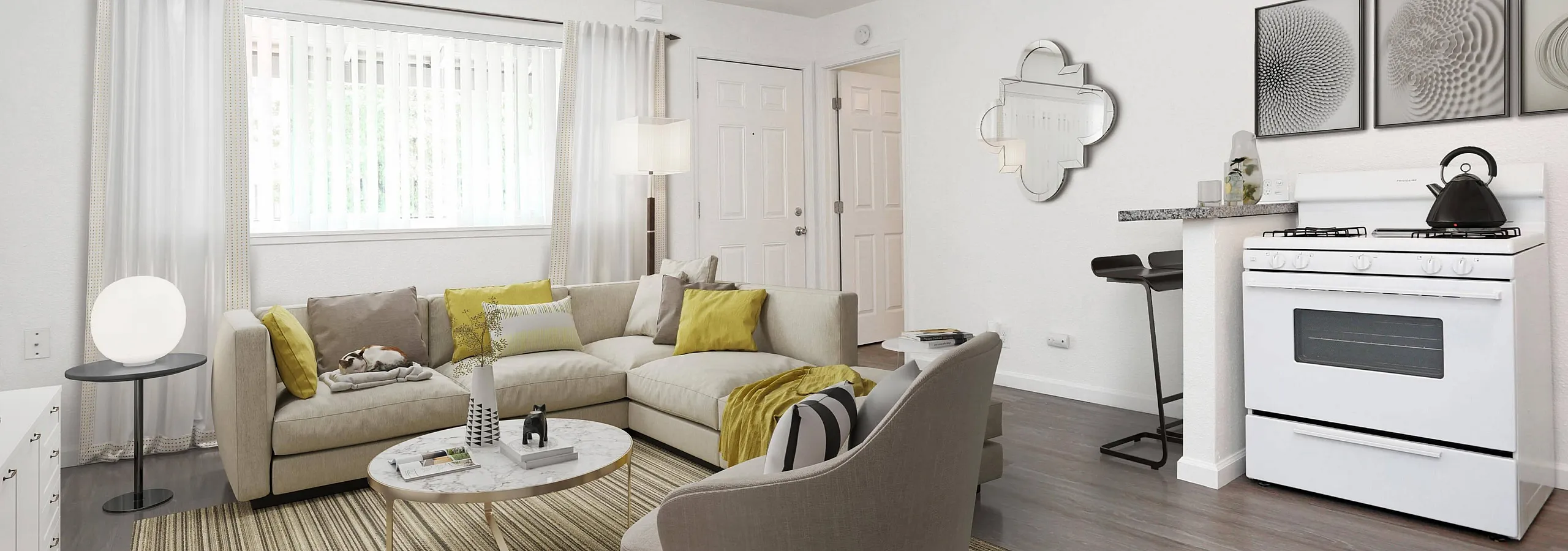 Living room with a beige couch and chair with yellow accents with kitchen stove to the right