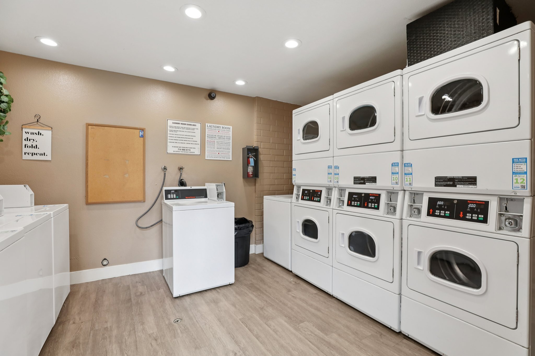 Modern laundry room with stacked washers and dryers, featuring bright lighting and a clean, organized space.