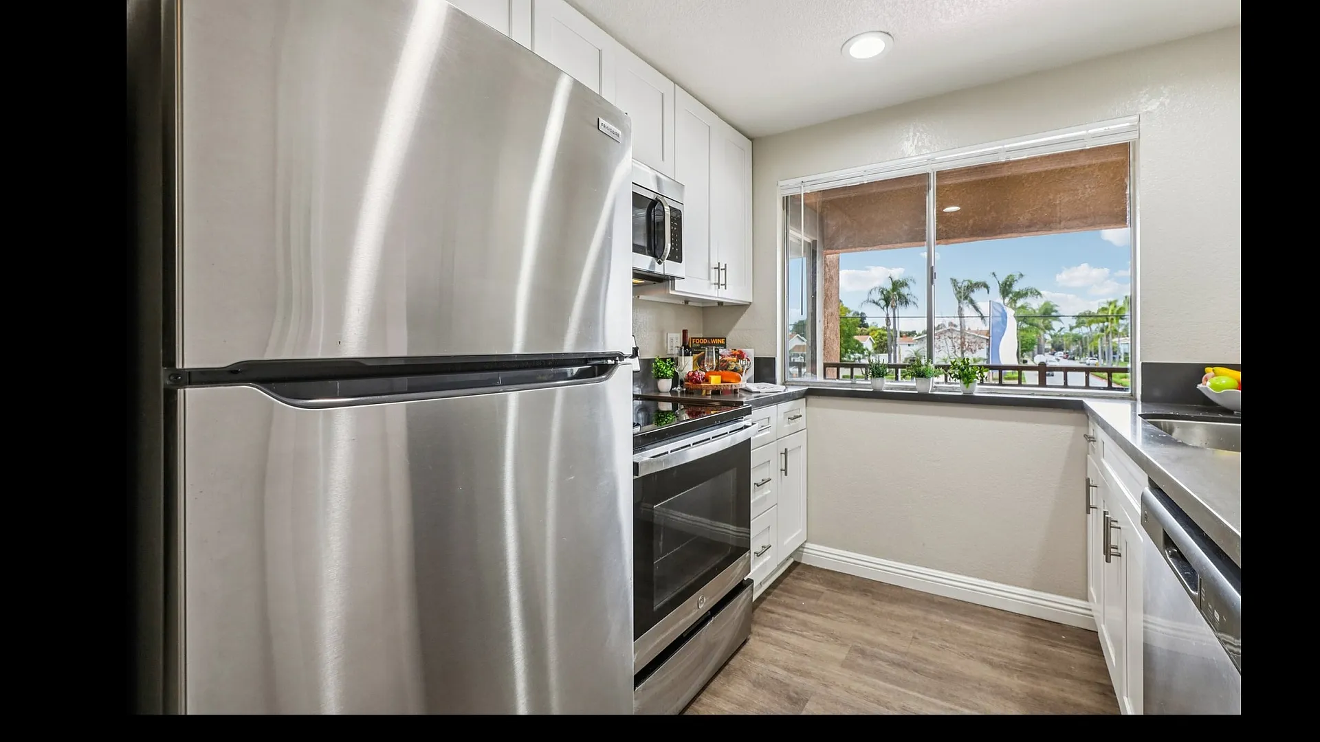Modern kitchen with stainless steel appliances, sleek white cabinetry, and a bright window view.